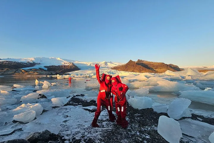 Person floating in a dry suit beside icebergs on a Fjallsárlón glacier lagoon boat tour in South East Iceland
