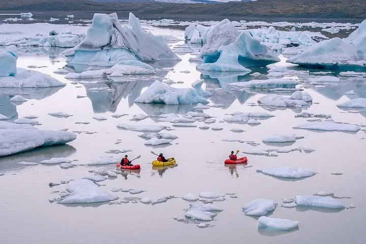Small group of kayaks near blue icebergs on a Jökulsárlón glacier lagoon boat tour in South East Iceland