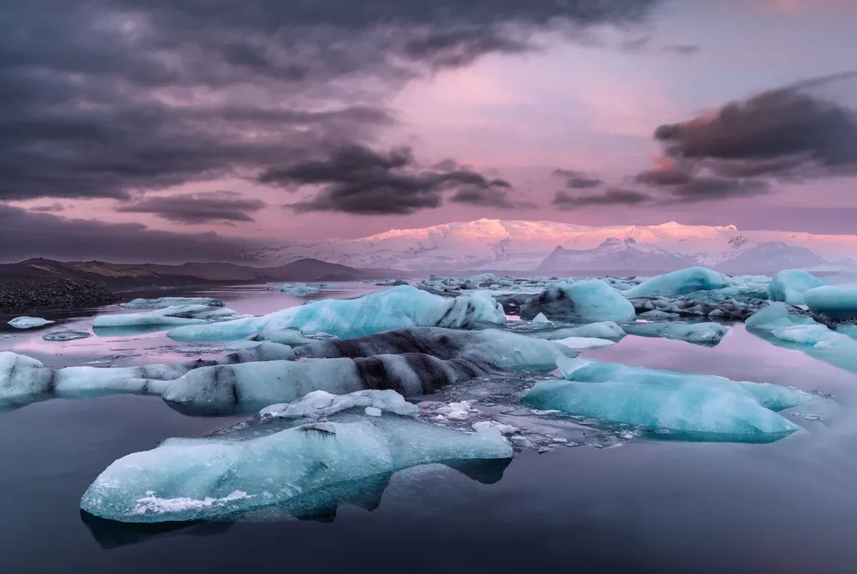 Jökulsárlón icebergs at dawn under a pink sky, seen on a glacier lagoon boat tour